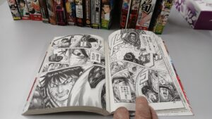 キングダムの紙の漫画を開いてページを読んでいる様子